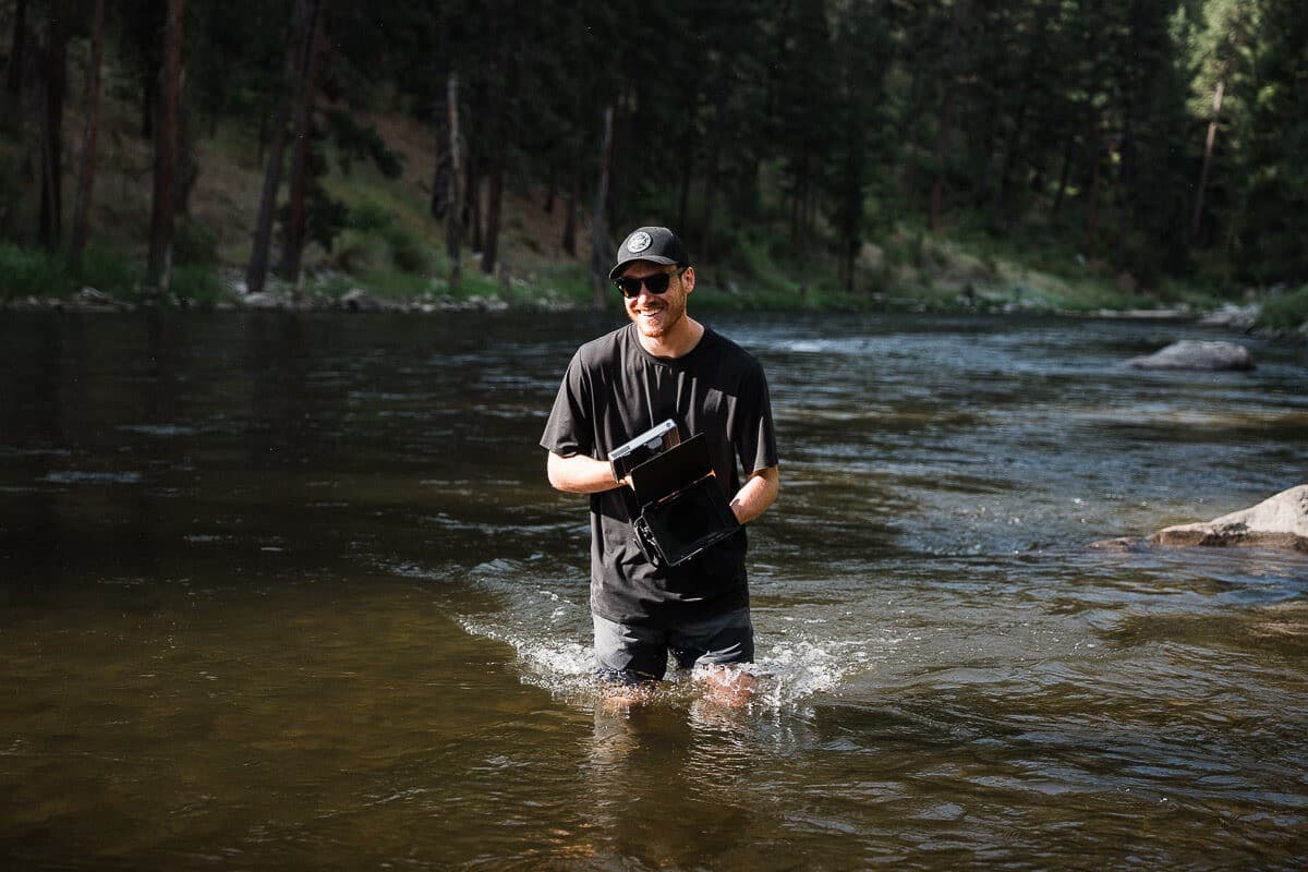 Mox creative director standing in a river holding a camera rig