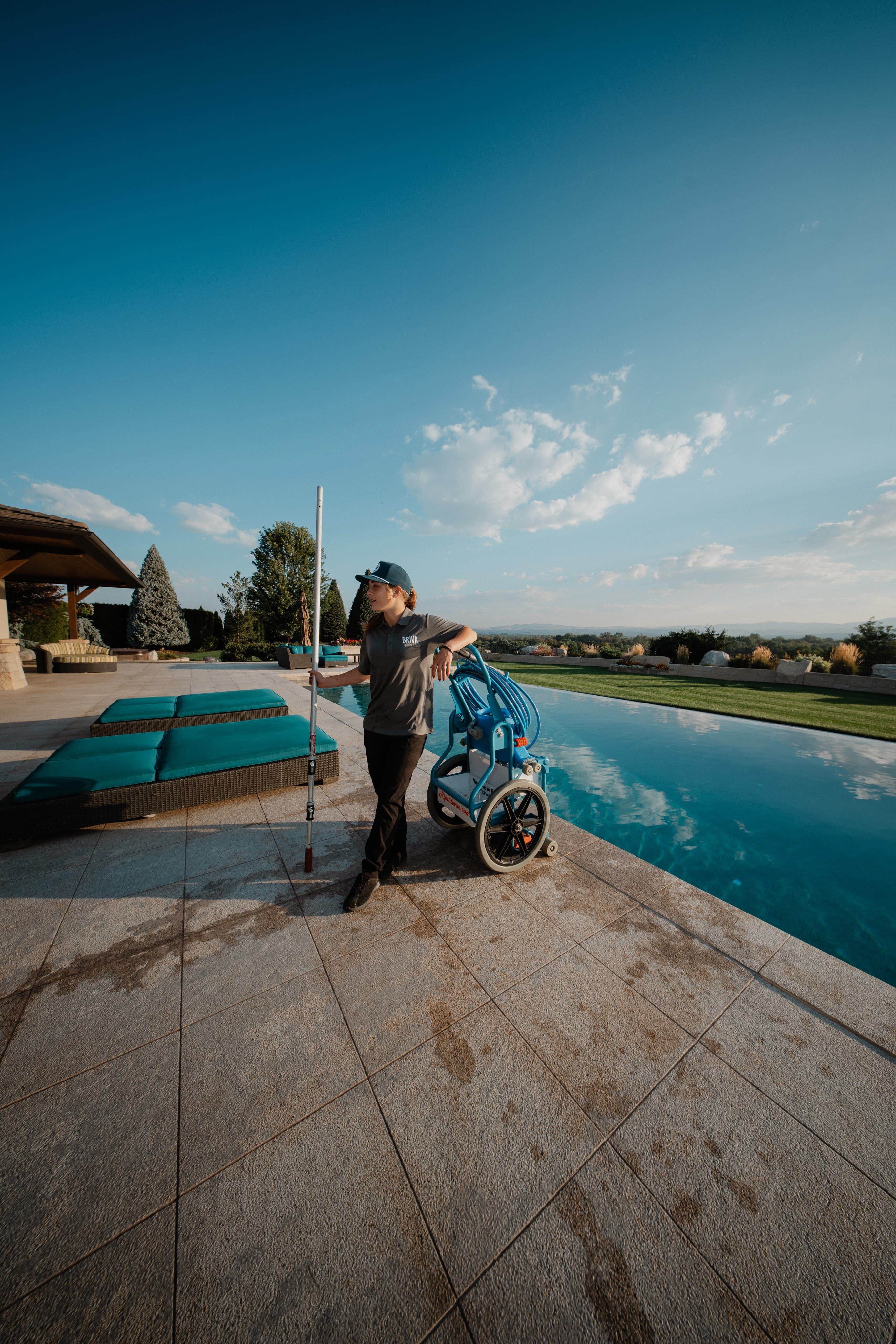 Pool technician leaning on equipment beside an infinity pool